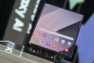 Foldable smartphone on a display stand, with a home screen full of colorful app icons and a weather widget.