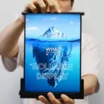 Person holding a tall rollable display showing an iceberg image and the words 'What you can see with a rollable display' on the screen.
