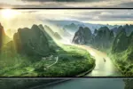 Smartphone screen showing a sunlit valley with green karst mountains and a winding river