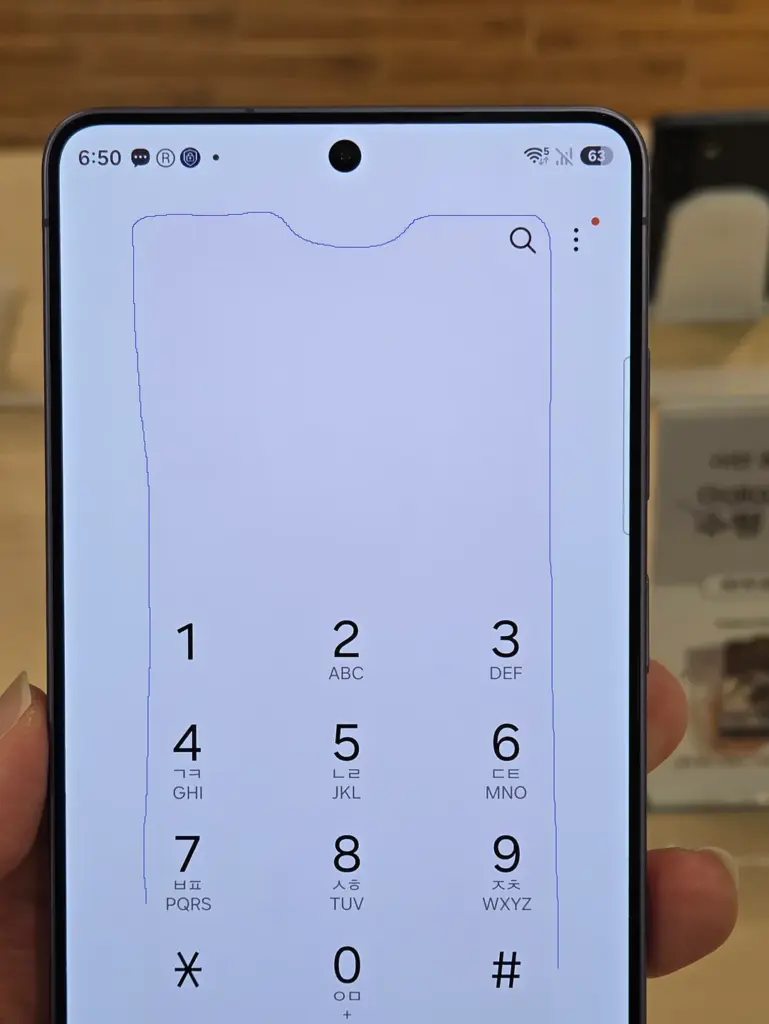Smartphone screen showing a phone dialer keypad with numbers 1–9, *, 0, # and letters beneath some digits (held in hand).
