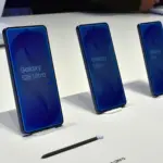 Row of blue Galaxy S26 Ultra/S26+/S26 smartphones on angled display stands in a bright showroom.