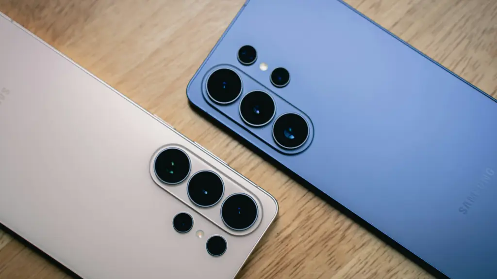 Two smartphones with multiple rear cameras on a wooden surface, showing large circular camera lenses arrayed in groups.