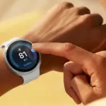 Close-up of a white smartwatch on the wrist, finger tapping the screen showing a health score of 81 and 'Excellent'.
