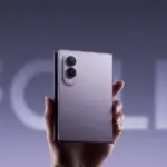 A hand holding a foldable smartphone with a dual-camera module on the back.