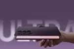 Hand holding a foldable smartphone with a triple-camera array against a purple background.