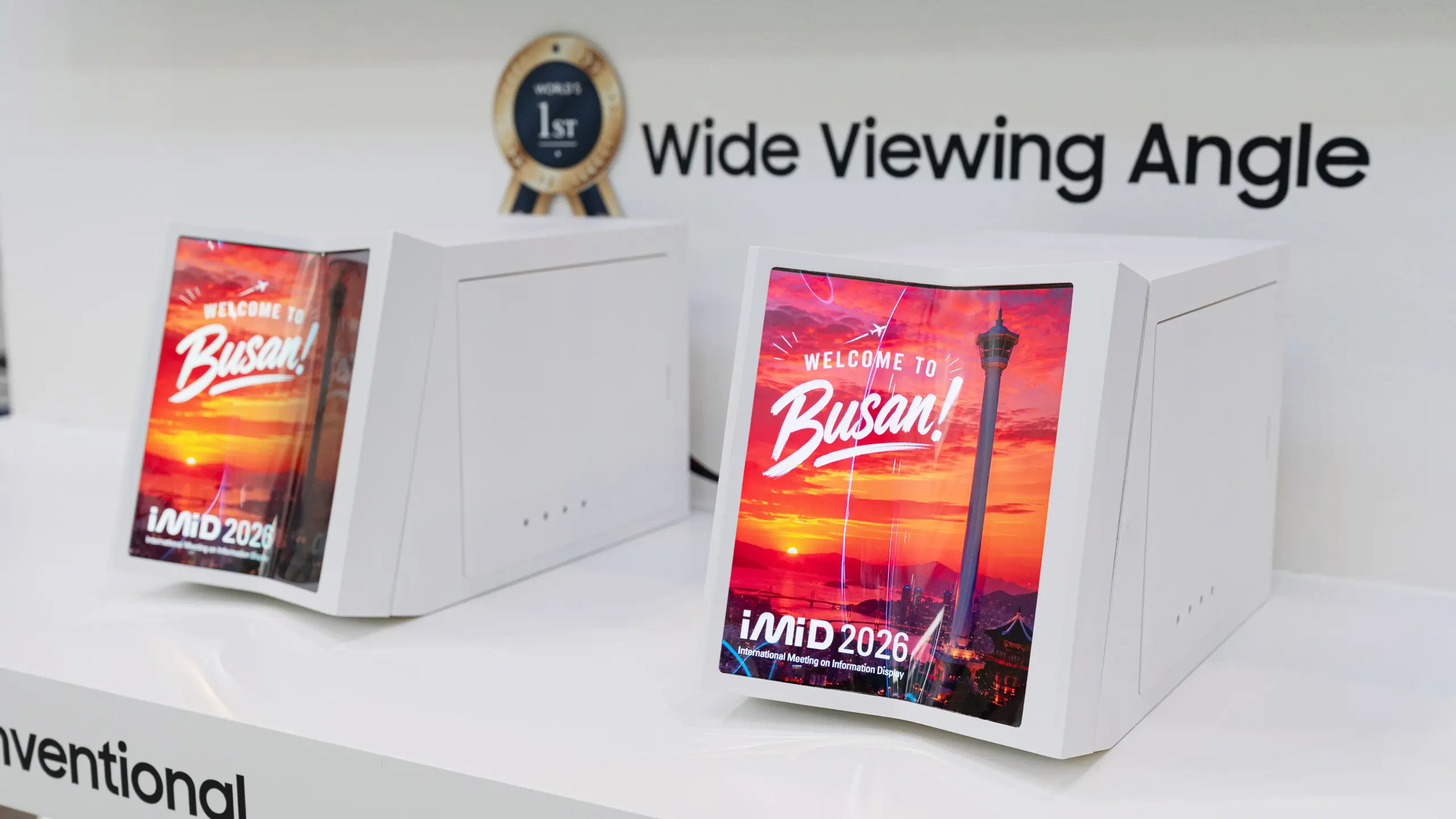 Displays showing colorful Busan posters on white kiosks with a 'Wide Viewing Angle' banner in the background.