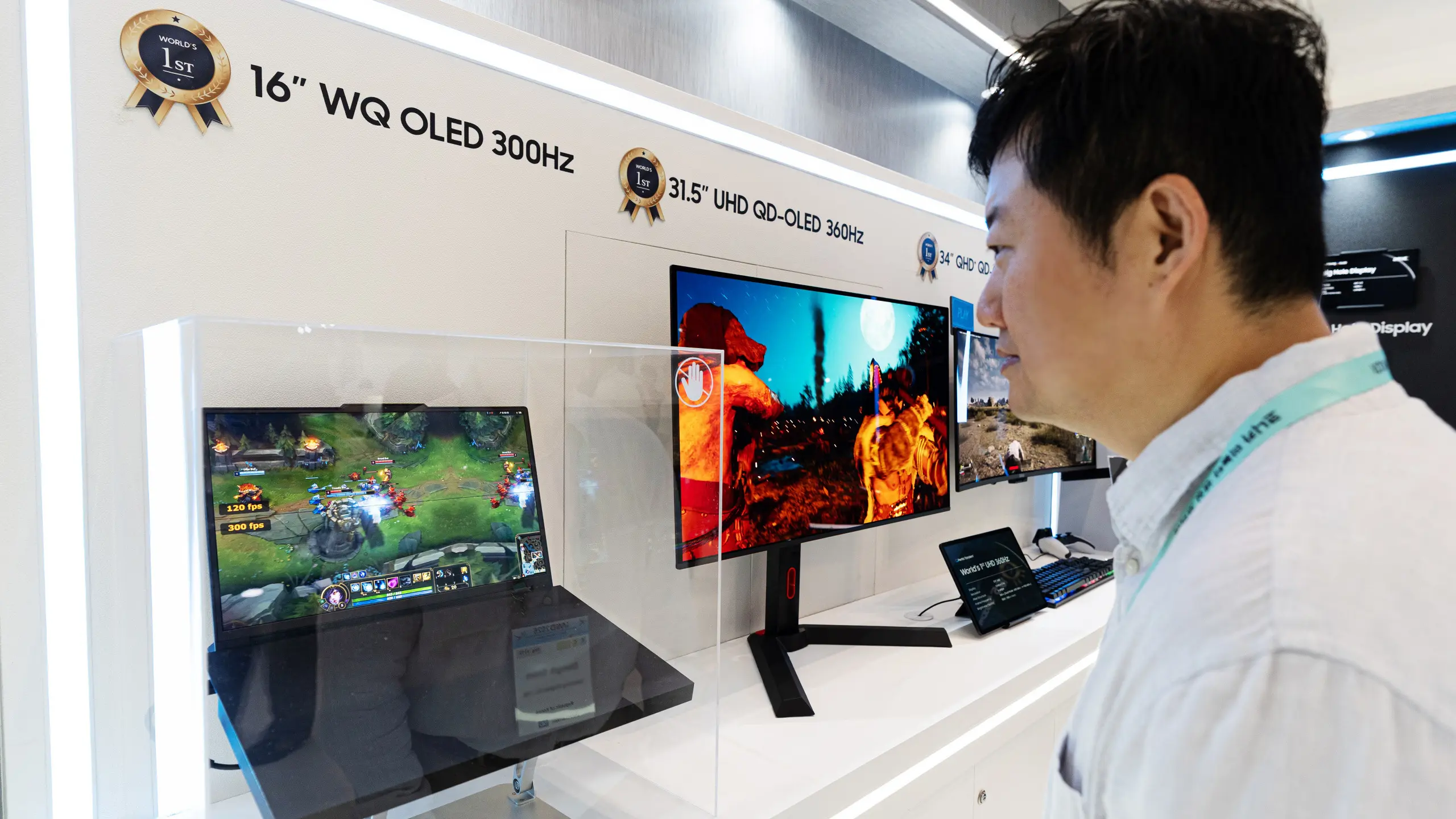Man in a white shirt examining a row of gaming displays at a showroom wall